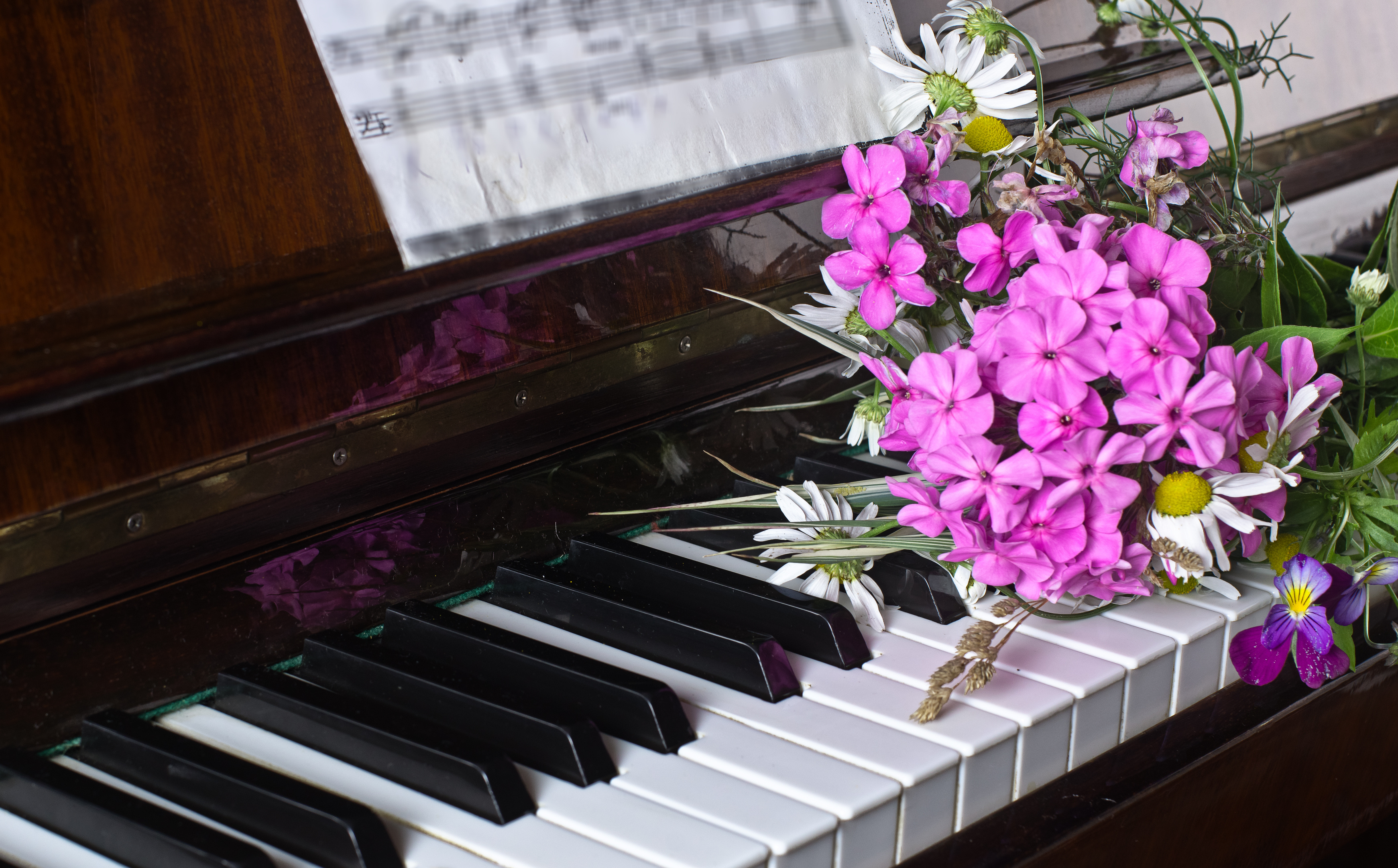 Piano, jonka päällä kesäisiä kukkia.