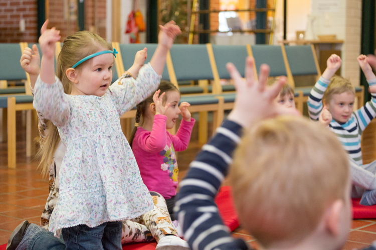 Lapsia ringissä kädet ylhäällä leikkimässä ja laulamassa.