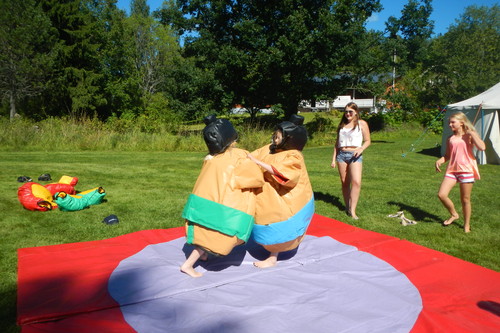 Kaksi lasta leikkii puhallettavissa sumopainijapuvuissa.