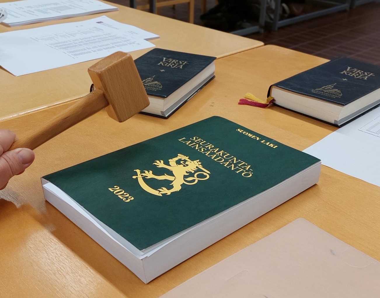 Pöydällä lakikirja ja puheenjohtajan nuija.