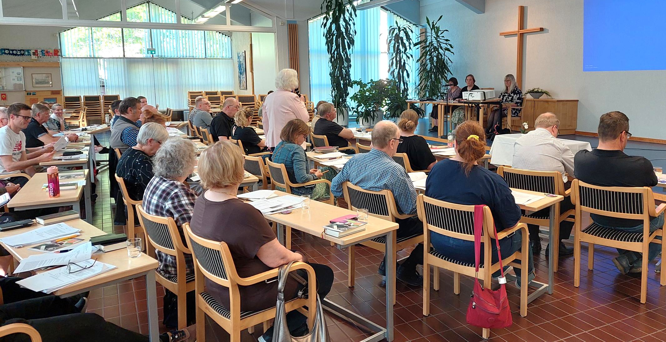Kokousväki koolla seurakuntasalissa.