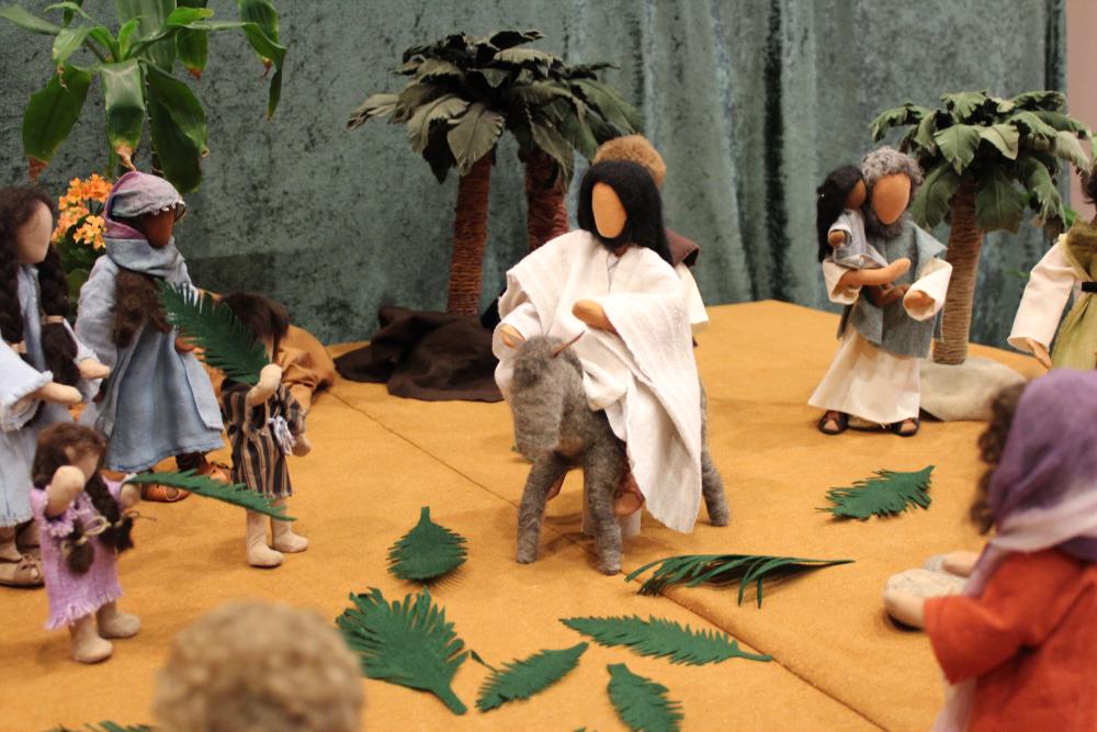 Pääsiäiskuvaelma, jossa Jeesus ratsastaa aasilla ja maahan on laskettu palmun lehtiä.