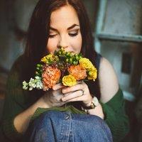 Nuori nainen istuu värikäs kukkakimppu käsissään.