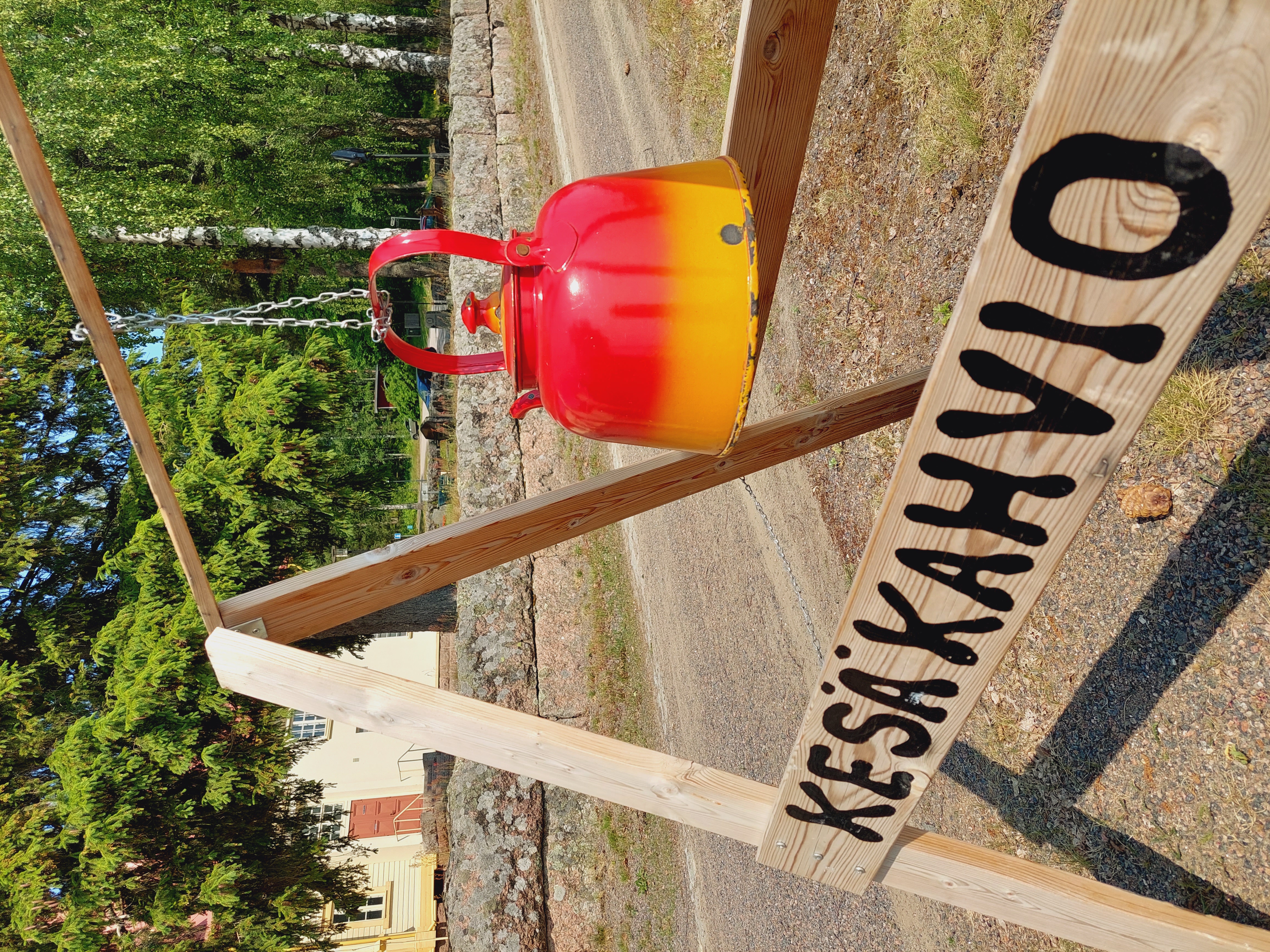 Kahvipannu etualalla tekstinään kesäkahvio, taustalla Jaalan kirkko