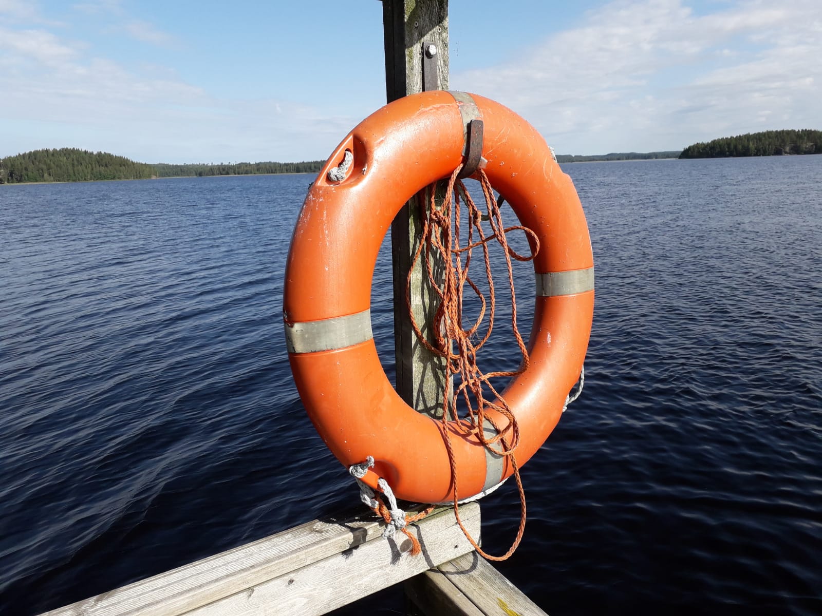 Kouvolan seurakunnan perheleiri Pelastusrengas Puhjonrannan leirikeskuksen laiturilla ja takana järvimaisema.