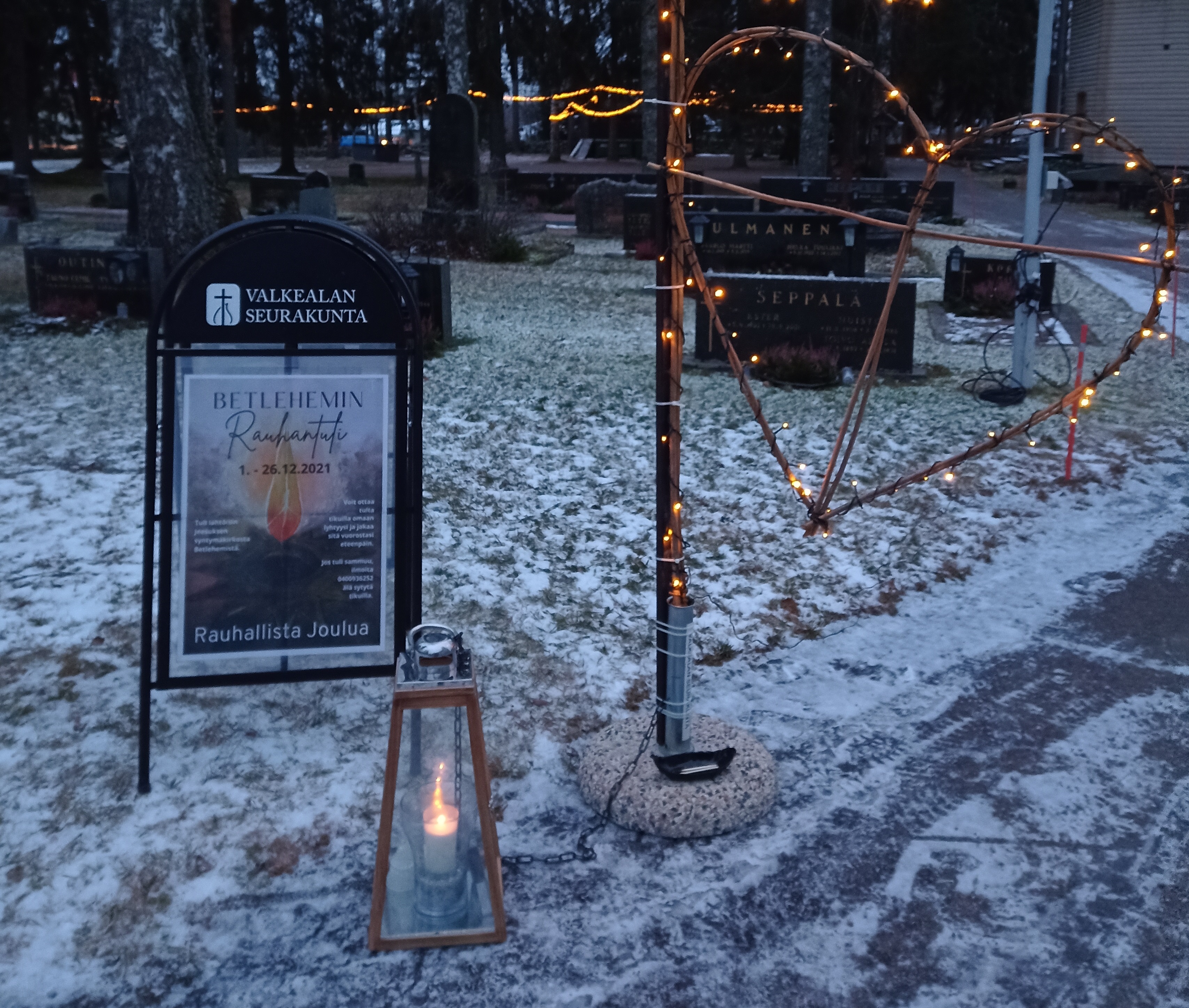 Kynttilä palaa lyhdyssä hautausmaalla.