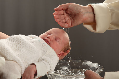 Pientä vauvaa kastetaan.