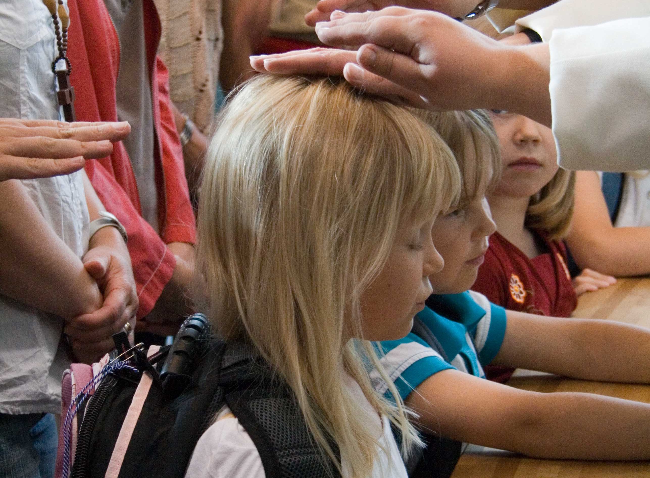 Ekaluokkalainen tyttö polvistuneena alttarille koulutielle siunaamisessa.