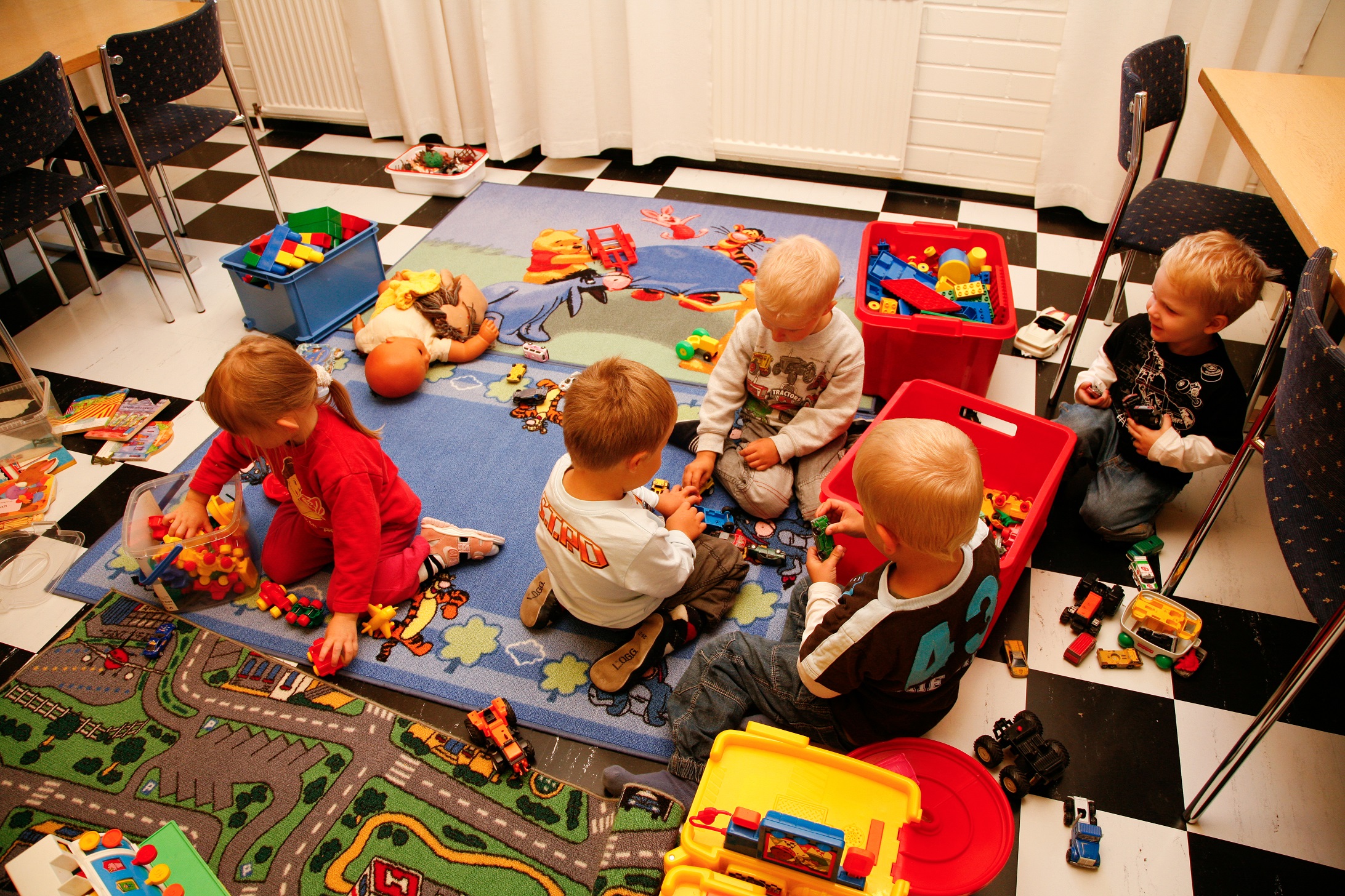Lapset leikkimässä kerhotilan lattialla leluilla.