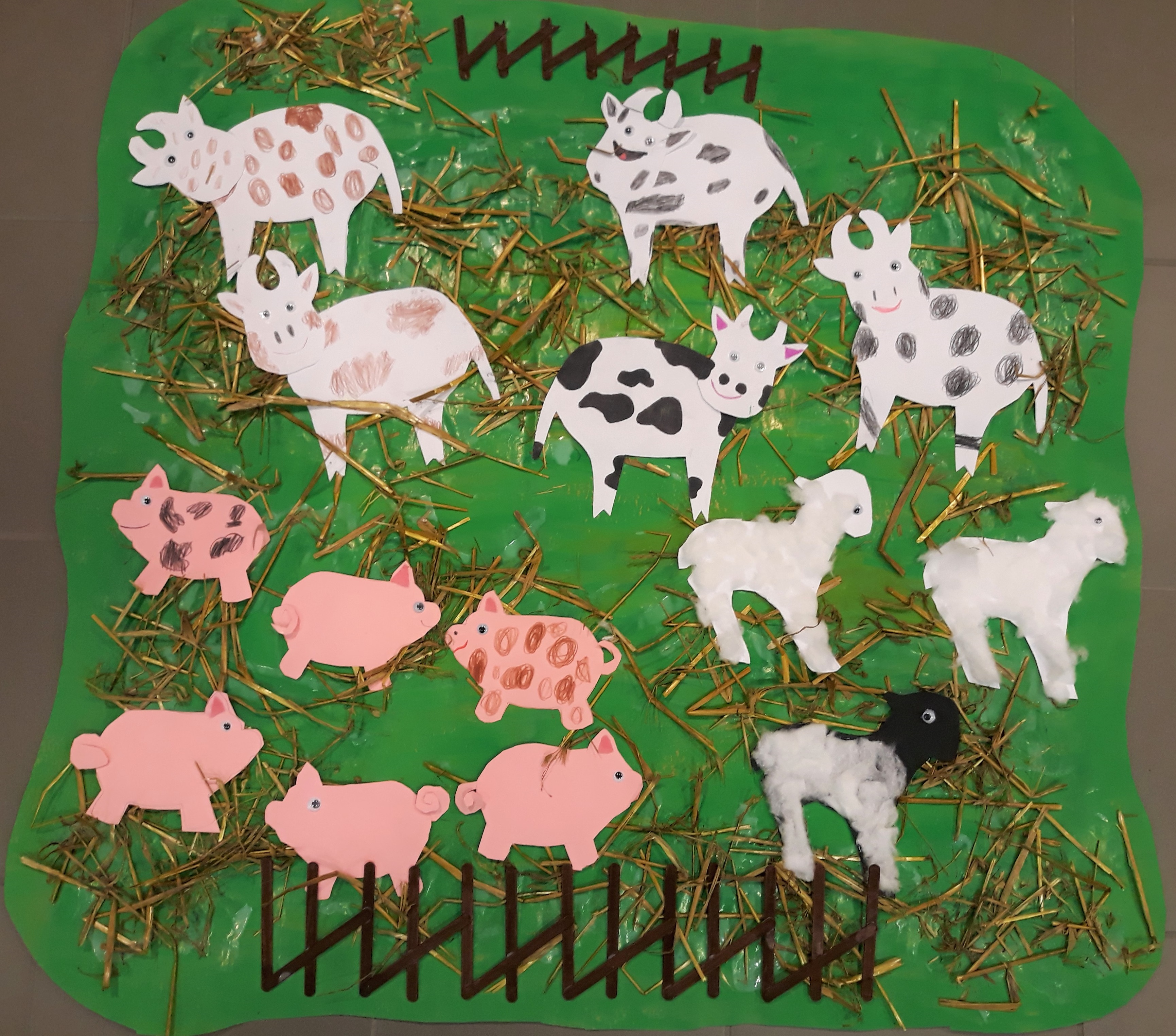 Paperinen kollaasityö, jossa on lehmiä ja possuja vihreällä pohjalla.