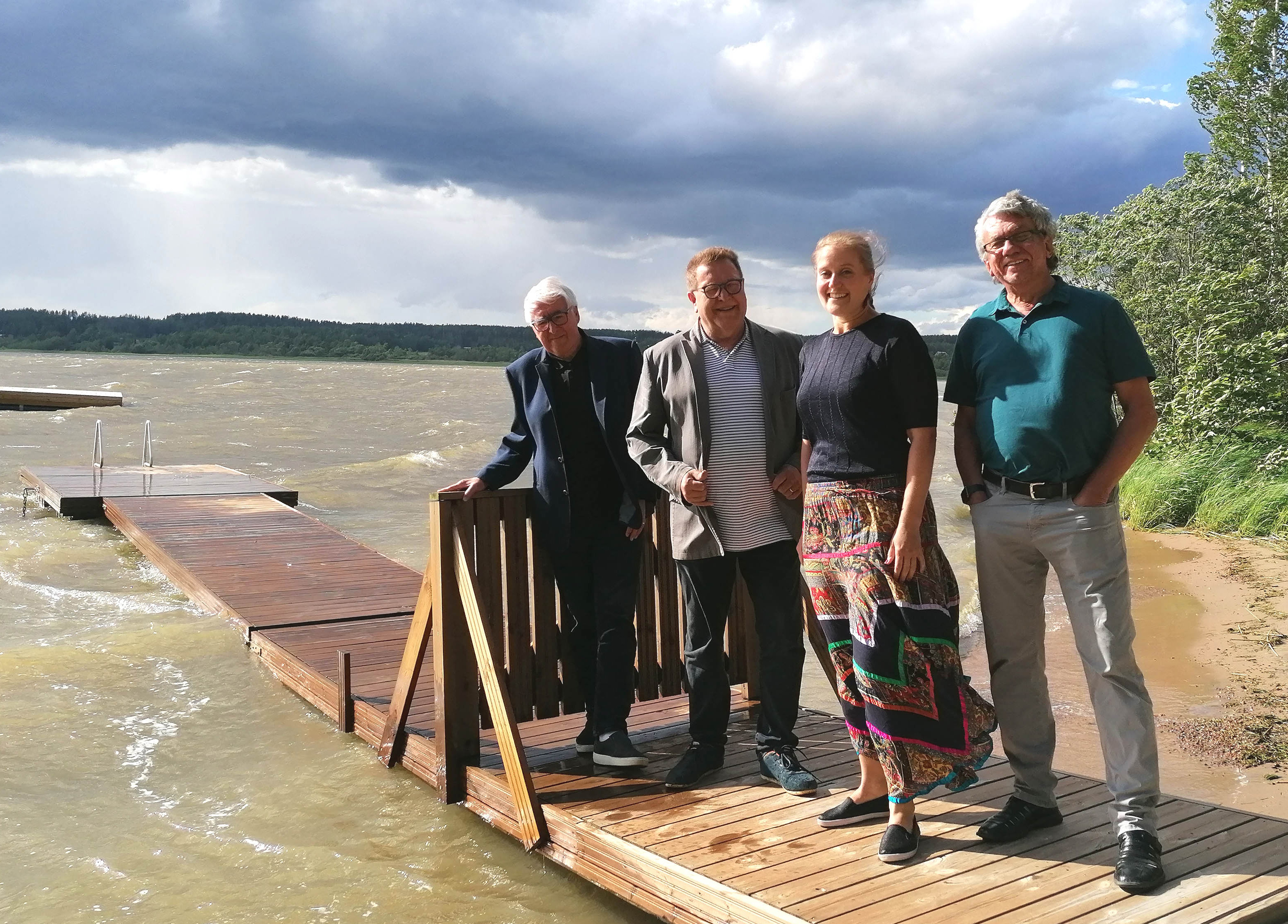 Kansanlaulukirkon muusikot seisovat laiturilla tuulisen Jaalanlahden rannalla.