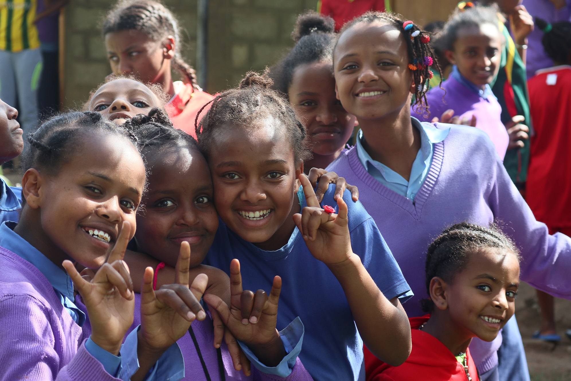 Ryhmäkuvassa iloisia tyttöjä koulupuvuissaan koulun pihalla.