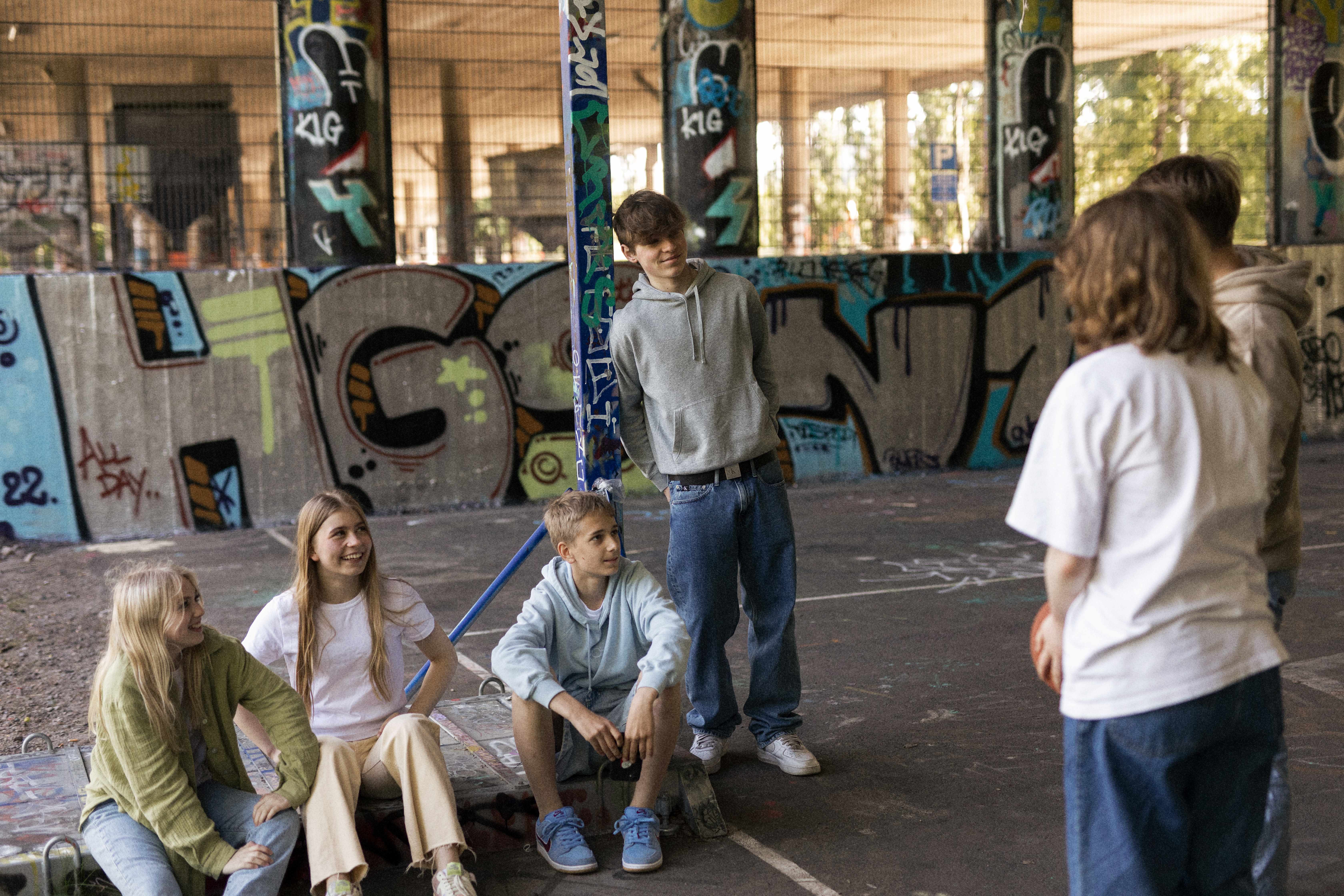 Nuorten ryhmä juttelemassa, taustalla graffitimaalauksia.
