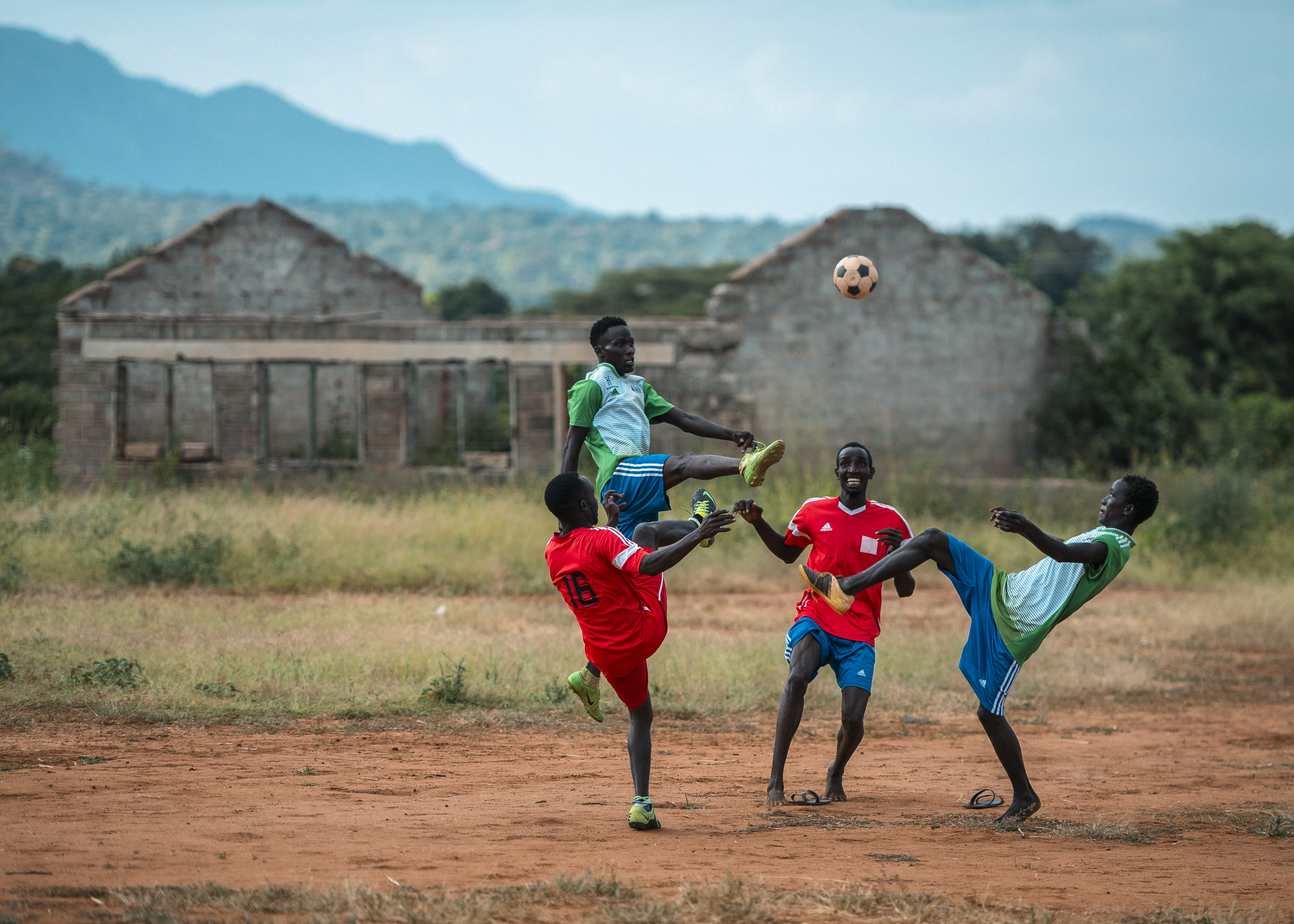 Neljä poikaa pelaa jalkapalloa.