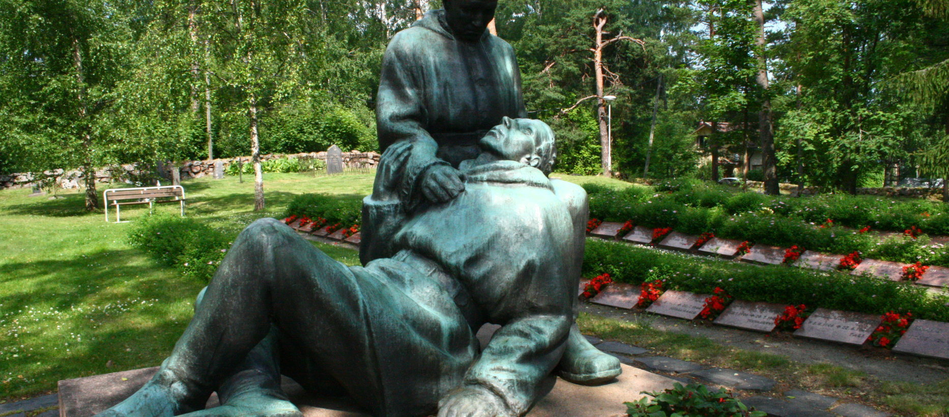 Elimäen kirkkotarha Kirkkotarhan patsas sekä sankarihaudat kukitettuna.