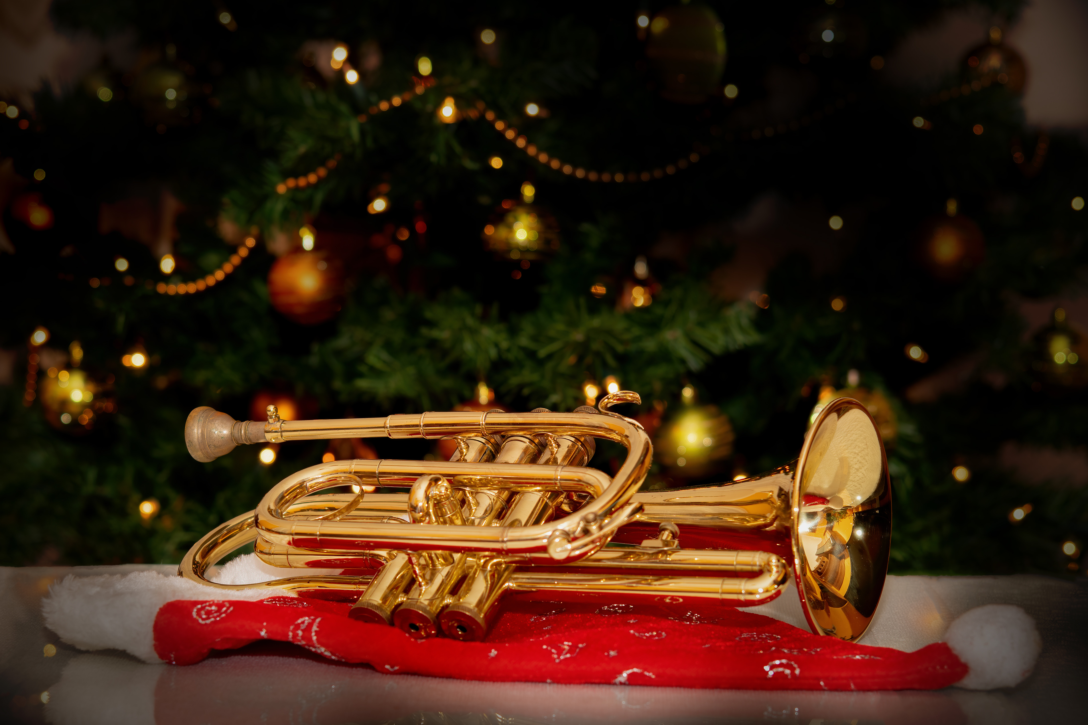 Trumpetti lepää pöydällä tonttulakin päällä, taustalla on joulukuusi.