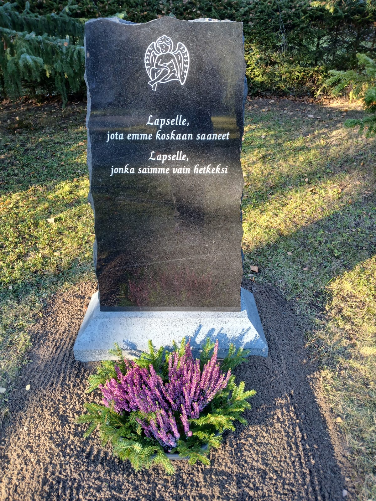Musta hautapaasi, jossa lukee:
