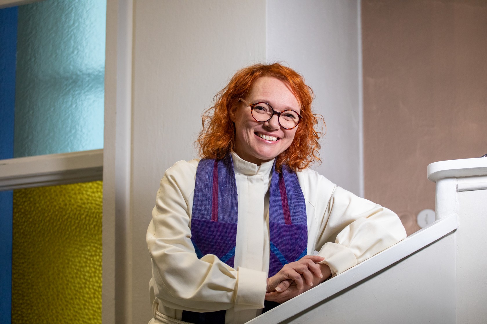 Mari Parkkinen seisoo nojaten porraskaiteeseen päällään alba.