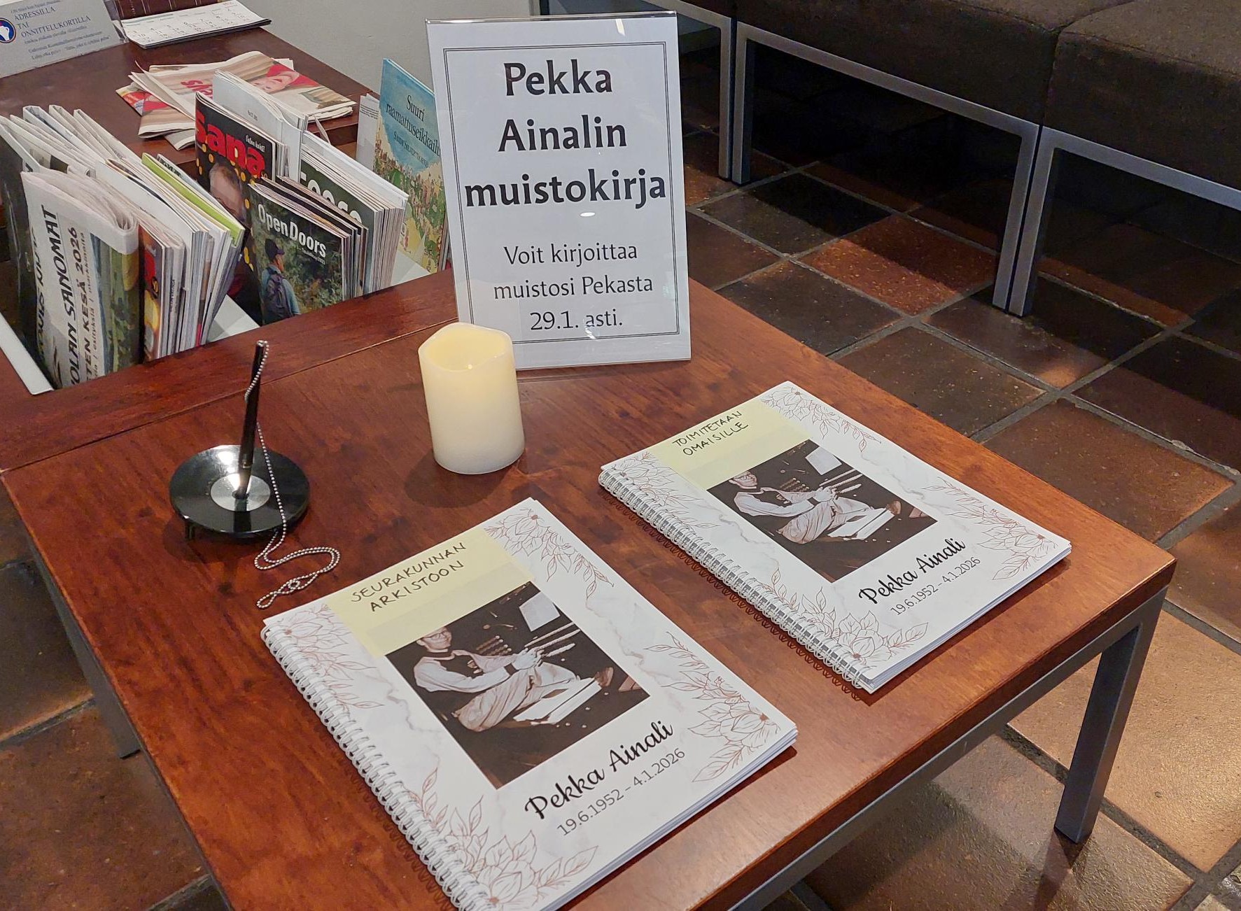 Kaksi muistokirjaa ja kynttilä pöydällä.