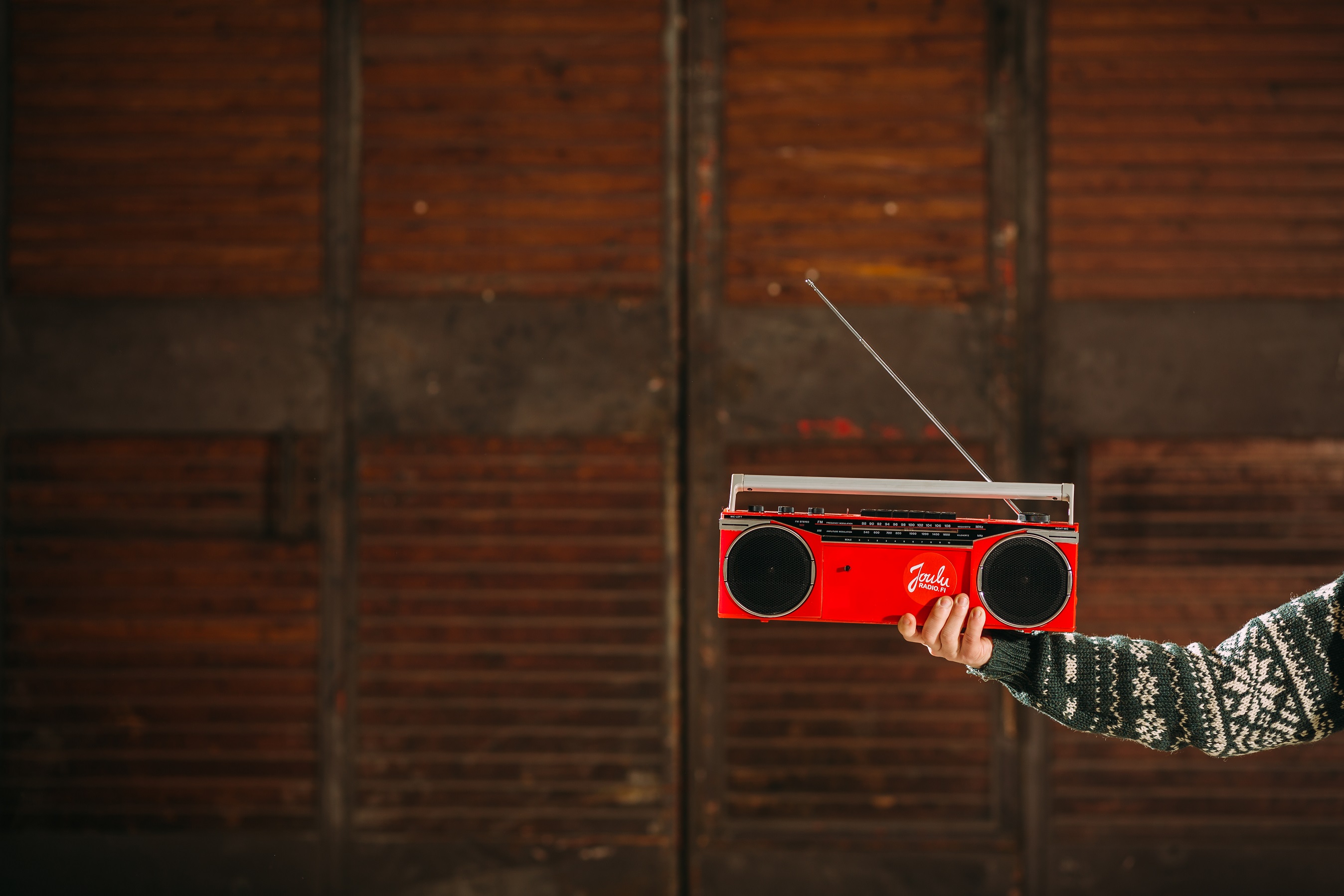 Käsi, joka pitelee punaista radiota.